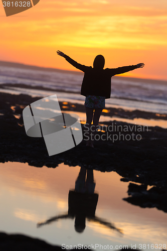 Image of Free woman enjoying freedom on beach at sunset.