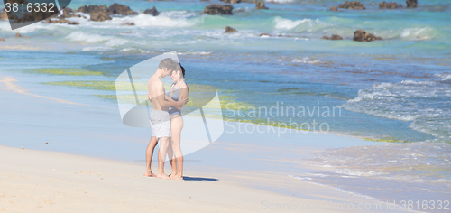 Image of Young couple kissing on sandy beach.