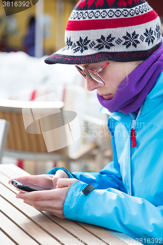 Image of Woman in ski resort using smartphone.