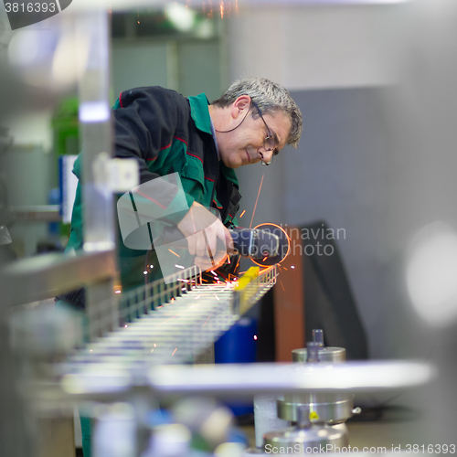 Image of Industrial worker grinding in manufacturing plant.