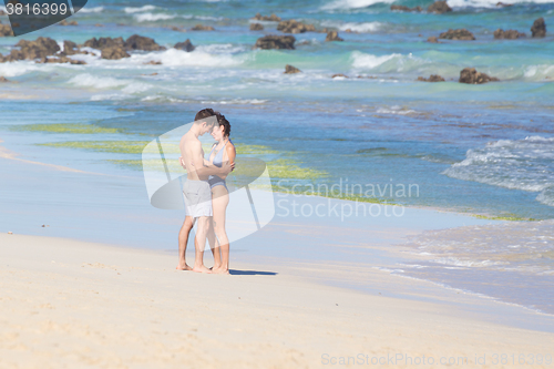 Image of Young couple kissing on sandy beach.