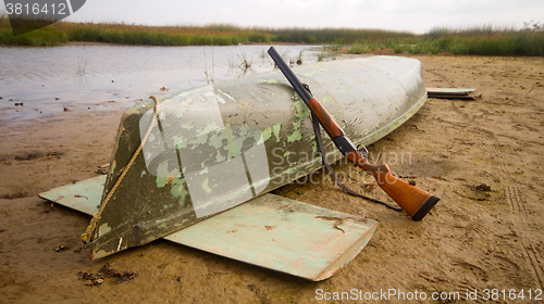 Image of main equipment of undemanding ducks hunter - canoe and shotgun