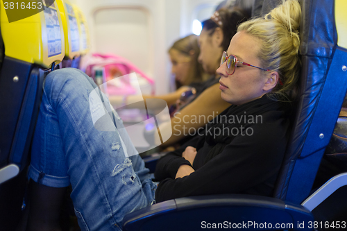 Image of Tired lady napping on airplane.