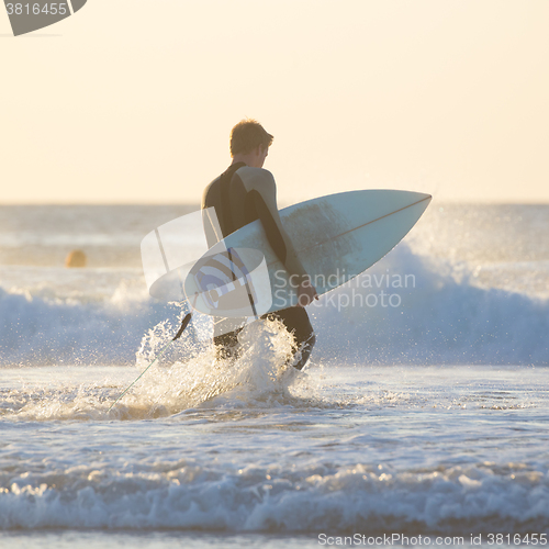 Image of Silhouette of surfer on beach with surfboard.