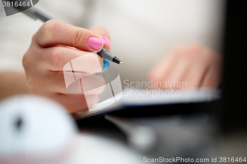 Image of female hands with pen writing on notebook