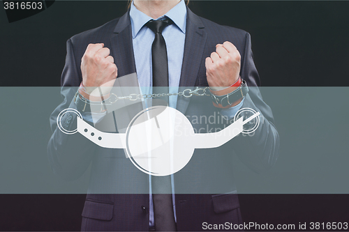 Image of man in a business suit with chained hands. handcuffs for sex games. concept of erotic entertainment.