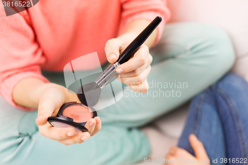 Image of close up of woman with makeup brush and blush