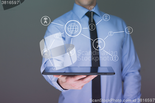 Image of businessman holding a tablet pc. Shows telecommunication towers. communication concept