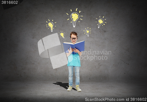 Image of happy little girl in eyeglasses reading book