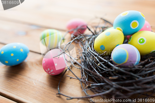 Image of close up of colored easter eggs in nest on wood