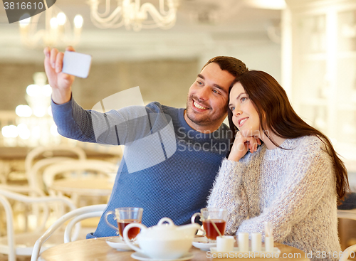 Image of couple taking smartphone selfie at cafe restaurant