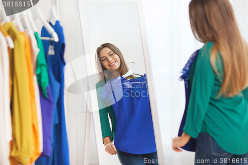 Image of happy woman choosing clothes at home wardrobe