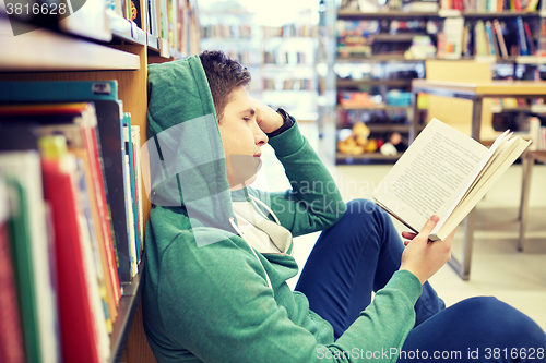 Image of student boy or young man reading book in library