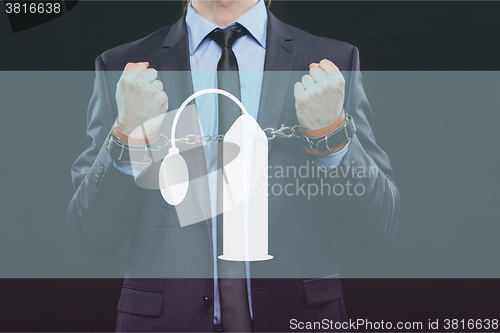Image of man in a business suit with chained hands. handcuffs for sex games. concept of erotic entertainment.