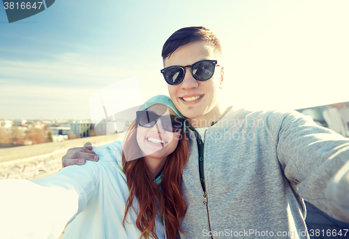 Image of happy teenage couple taking selfie on city street