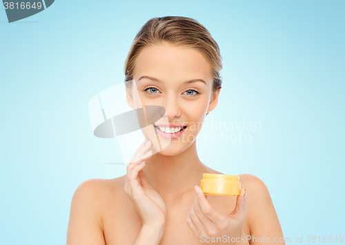 Image of happy young woman applying cream to her face