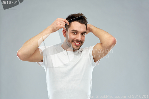 Image of happy man brushing hair with comb over gray