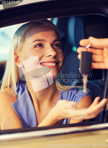 Image of happy woman getting car key in auto show or salon