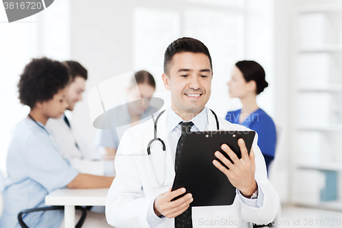 Image of happy doctor with clipboard over medical team