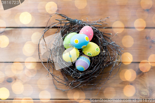 Image of close up of colored easter eggs in nest on wood