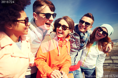 Image of smiling friends in sunglasses laughing on street