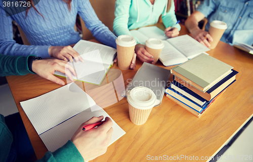 Image of close up of hands with books writing to notebooks