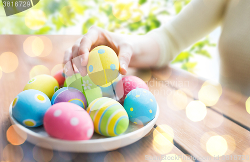 Image of close up of woman hands with colored easter eggs