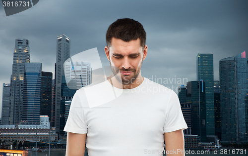 Image of unhappy man over evening singapore city background