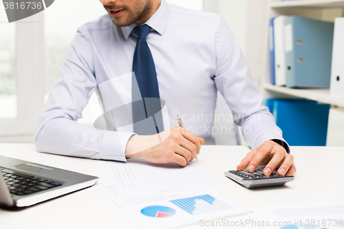 Image of close up of businessman with laptop and papers