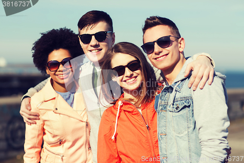 Image of happy teenage friends in shades hugging outdoors