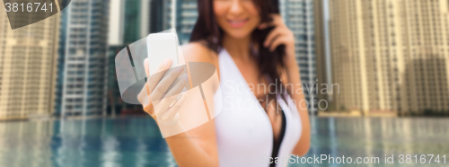 Image of woman taking selfie with smartphone over city pool