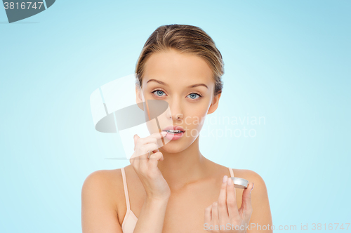 Image of young woman applying lip balm to her lips