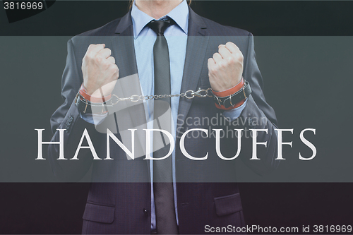 Image of man in a business suit with chained hands. handcuffs for sex games. concept of erotic entertainment.