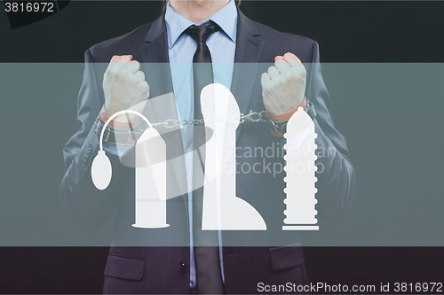 Image of man in a business suit with chained hands. handcuffs for sex games. concept of erotic entertainment.