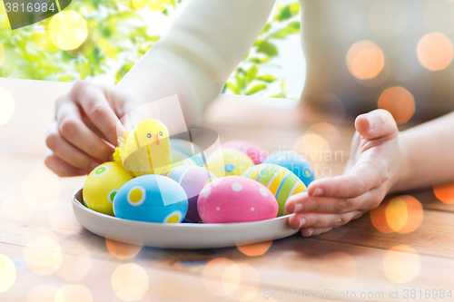 Image of close up of woman hands with colored easter eggs