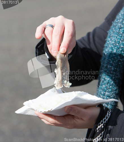 Image of Dutch woman is eating typical raw herring