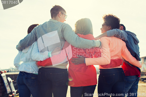 Image of group of happy teenage friends hugging on street