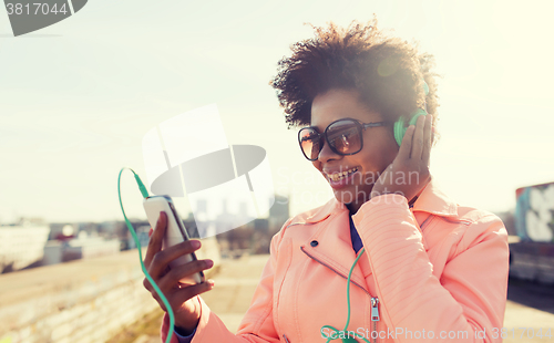 Image of happy young woman with smartphone and headphones