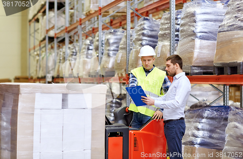 Image of worker and businessmen with clipboard at warehouse