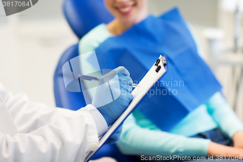 Image of close up of dentist with clipboard and patient