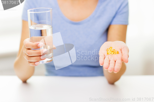 Image of close up of woman hands with capsules and water