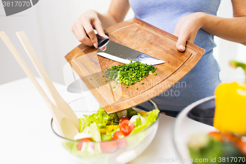 Image of close up of woman with chopped onion cooking salad