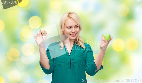Image of smiling woman choosing between apple and cookie