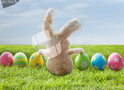 Image of close up of colored easter eggs and bunny on grass