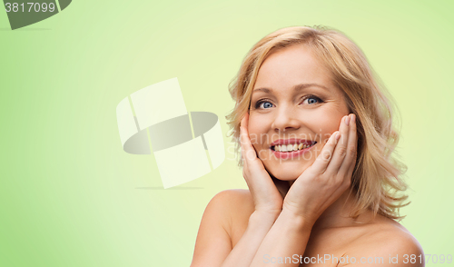 Image of smiling woman with bare shoulders touching face