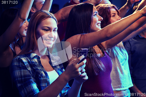 Image of woman with smartphone texting message at concert