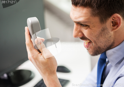 Image of angry businessman calling on phone in office