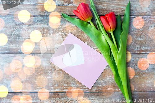 Image of close up of tulips and greeting card with heart