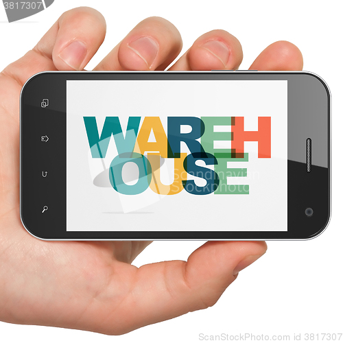 Image of Industry concept: Hand Holding Smartphone with Warehouse on  display