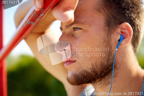 Image of young man with earphones and horizontal bar